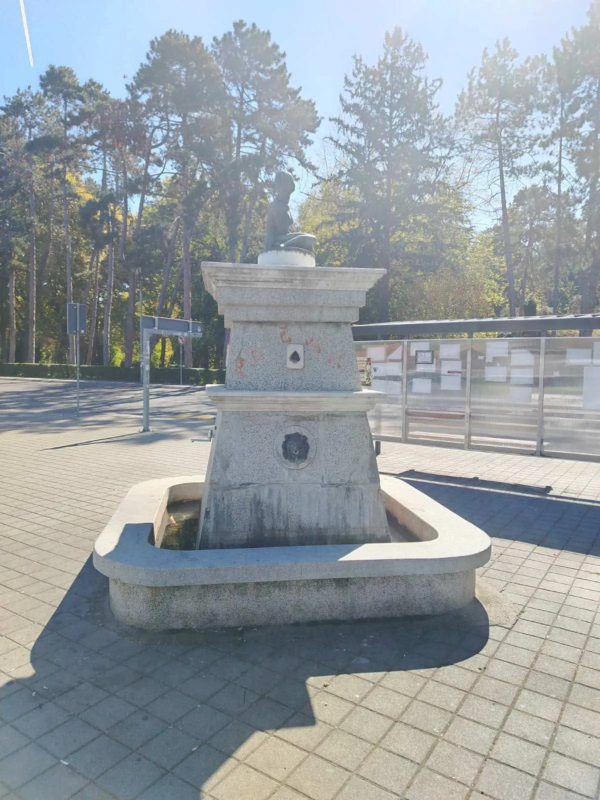Česma sa znakom pik, ženskom figurom i banjskim parkom u pozadini