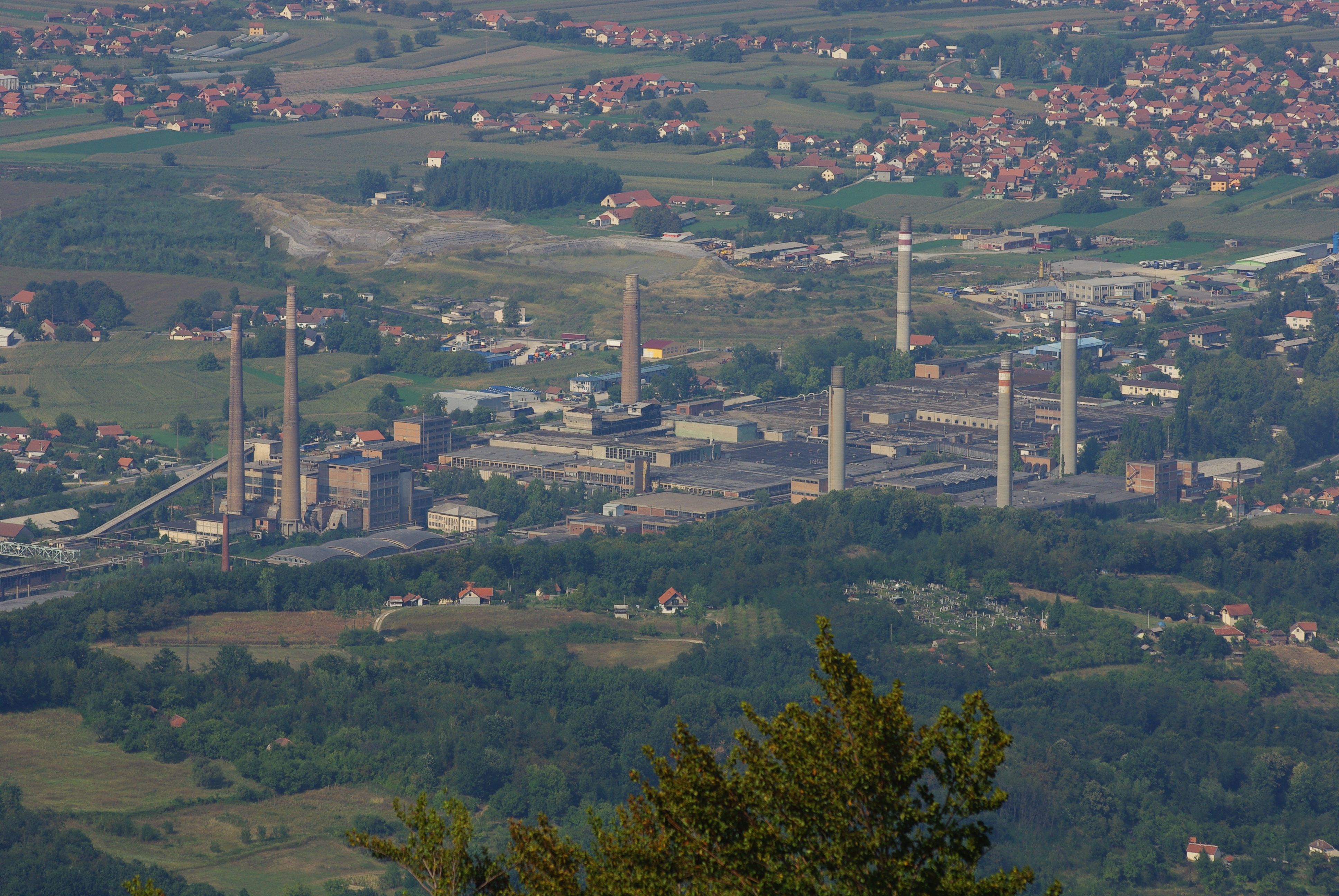 Pogled sa visine na hale i dimnjake Viskoze, okružene naseljima i njivama